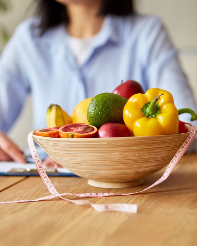 Nutritionist, dietitian woman writing a diet plan, with healthy vegetables and fruits, healthcare and diet concept. Female nutritionist with fruits working at her desk, workplace